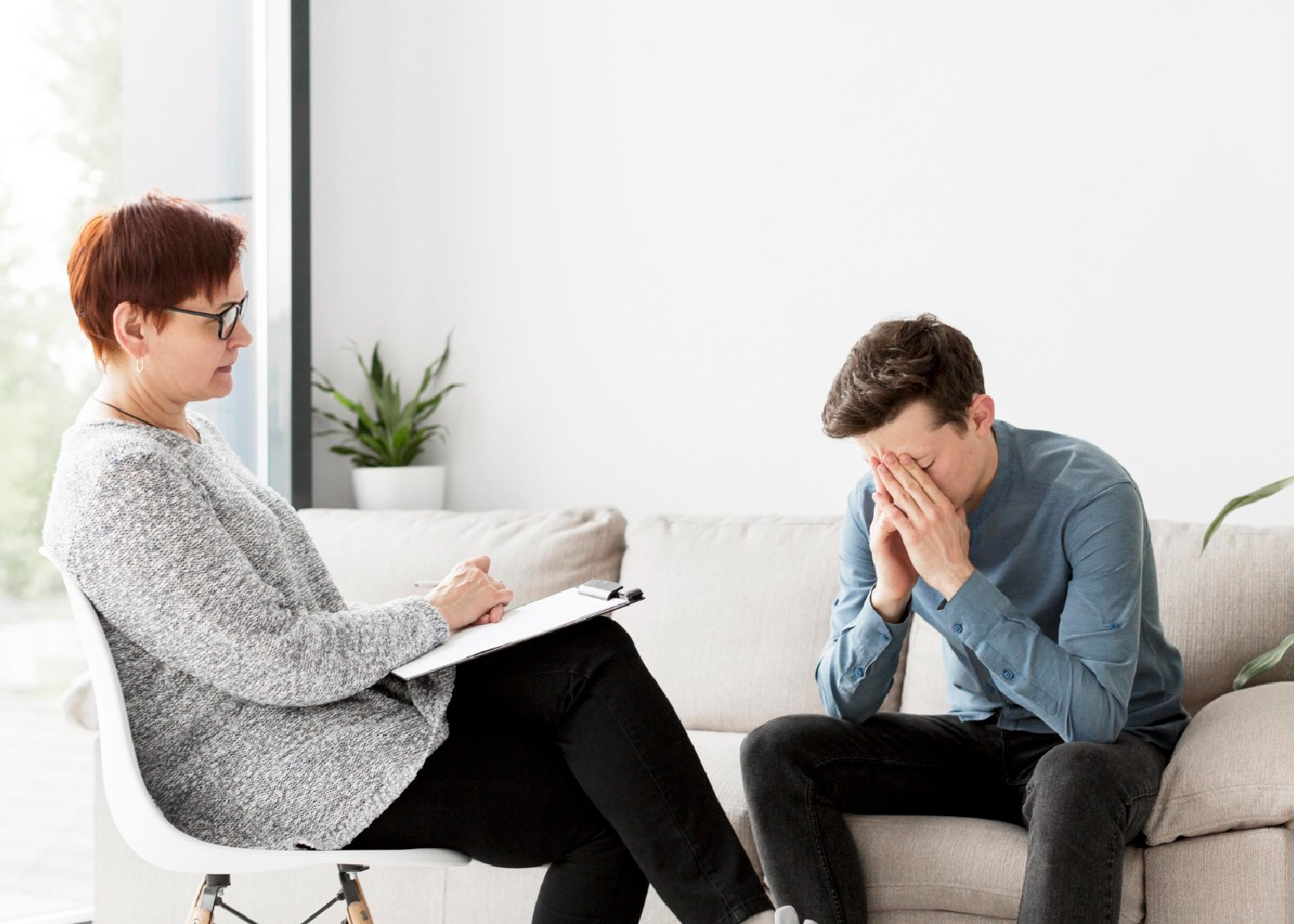 Young adult sitting quietly in a counselling session, reflecting emotions of overwhelm, fatigue, and vulnerability